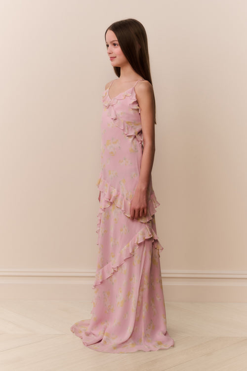 Young girl wearing a pink floral maxi dress against a plain background