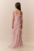 Girl wearing a pink floral dress with ruffled layers on a plain background