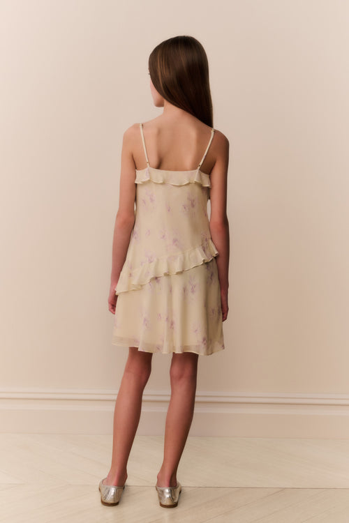 Woman wearing a light yellow dress with floral patterns against a beige background