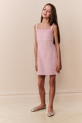 Young girl wearing pink sleeveless mini dress with scalloped lace neckline