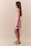 Young girl wearing pink sleeveless mini dress with scalloped lace neckline