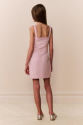Young girl wearing pink sleeveless mini dress with scalloped lace neckline