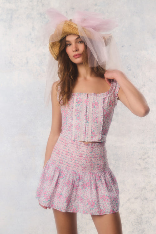 Woman wearing a floral dress and straw hat against a light background
