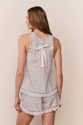 Woman wearing a light blue pajama set with lace details on a beige background