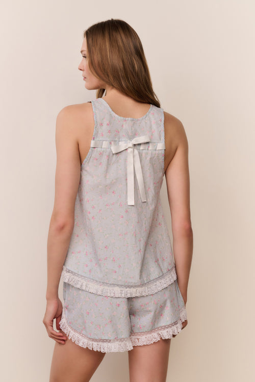 Woman wearing a light blue pajama set with lace details on a beige background