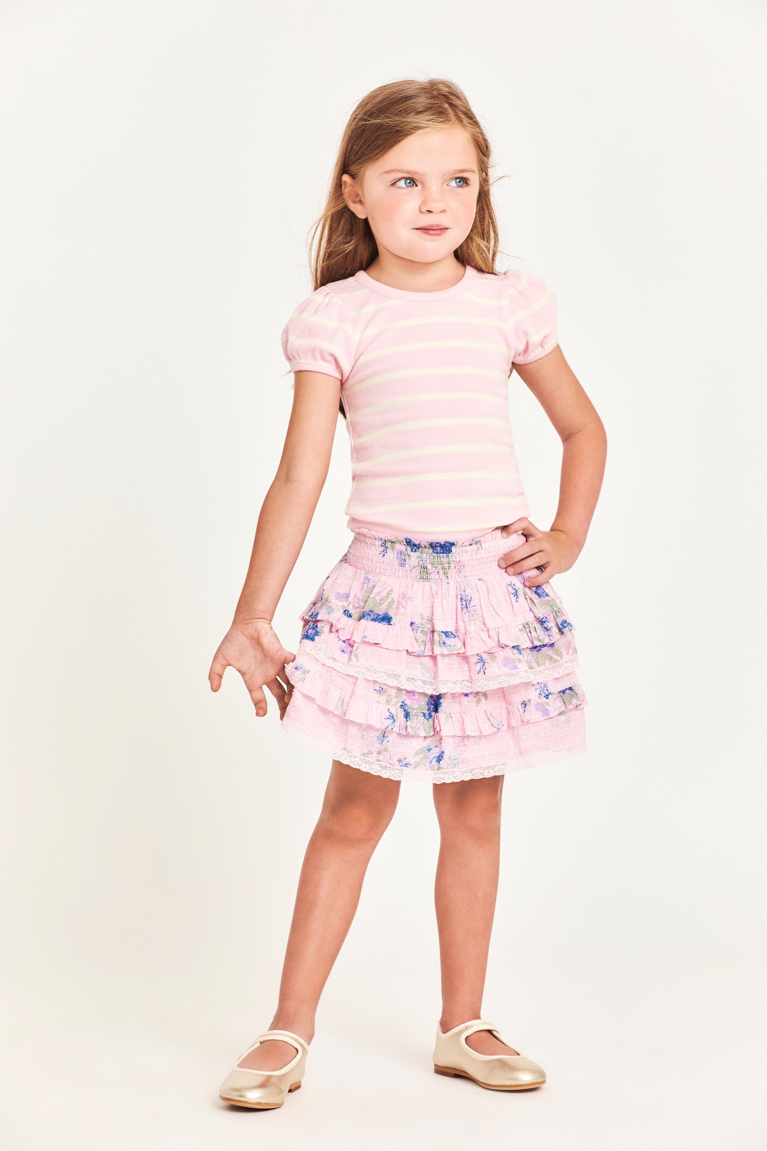 The Billie Skirt is 100% cotton and features a wide smocked waistband with two shirred tiers and ruffle detailing. It is a beautiful baby pink with blue flower detailing.  