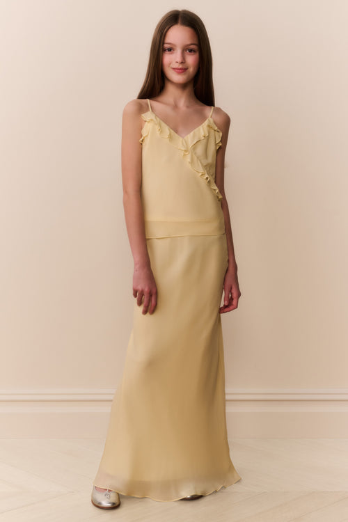 Girl wearing a light yellow top and matching long skirt against a beige background
