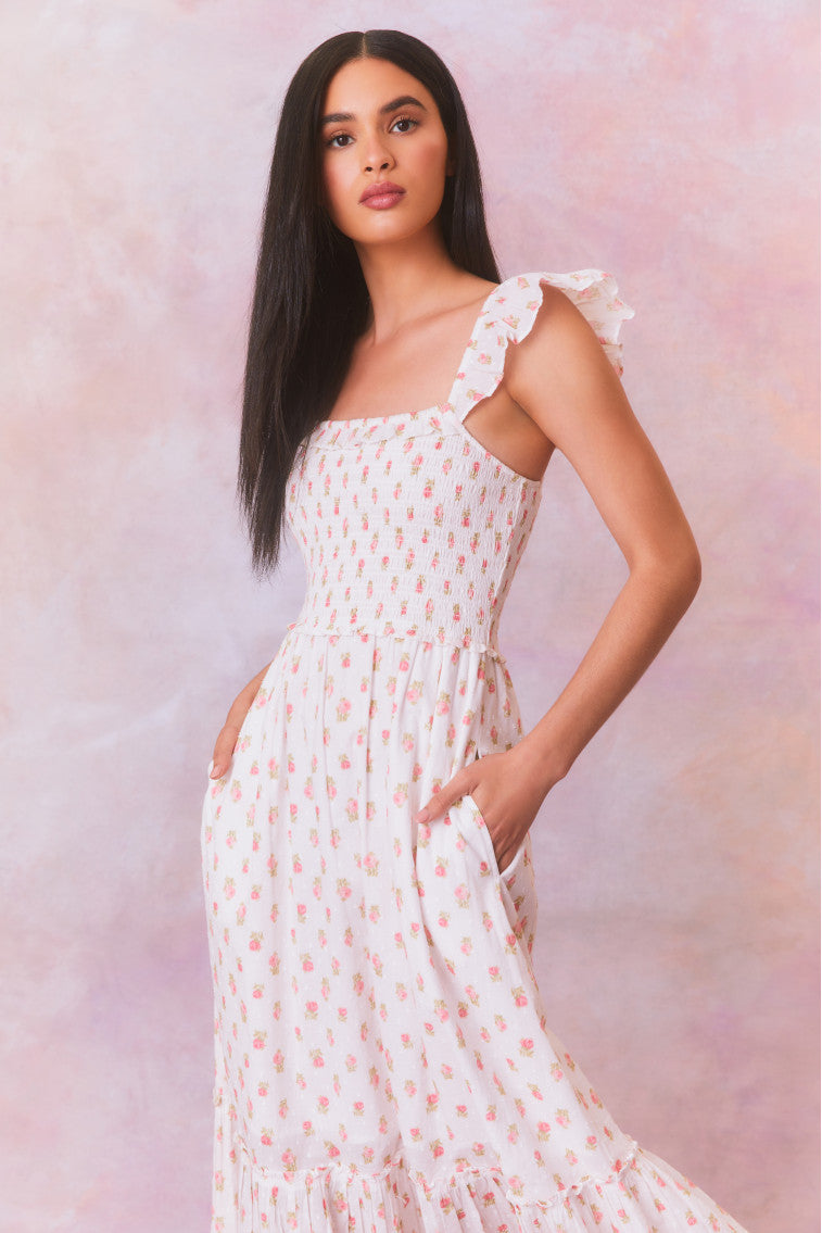 Floral printed maxi dress with ruffles on the shoulder that fall to a square neckline and an elastic smocked bodice that descends to a flouncy, sweeping skirt.