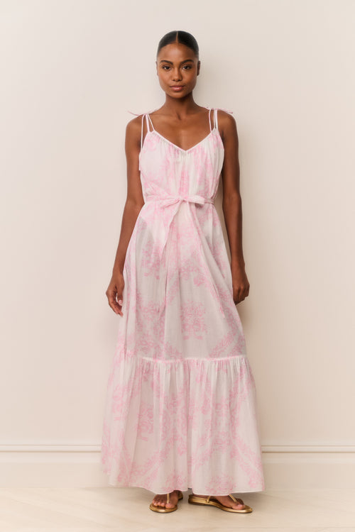 Woman wearing a pink and white patterned dress against a plain background