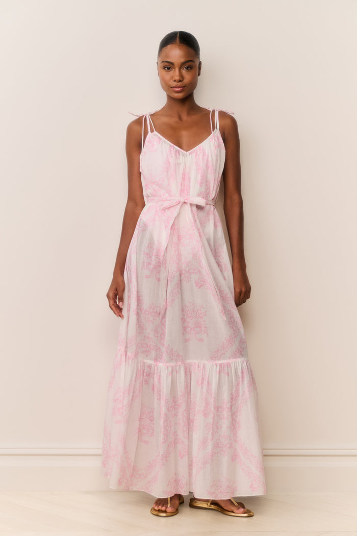 Woman wearing a pink and white patterned dress against a plain background