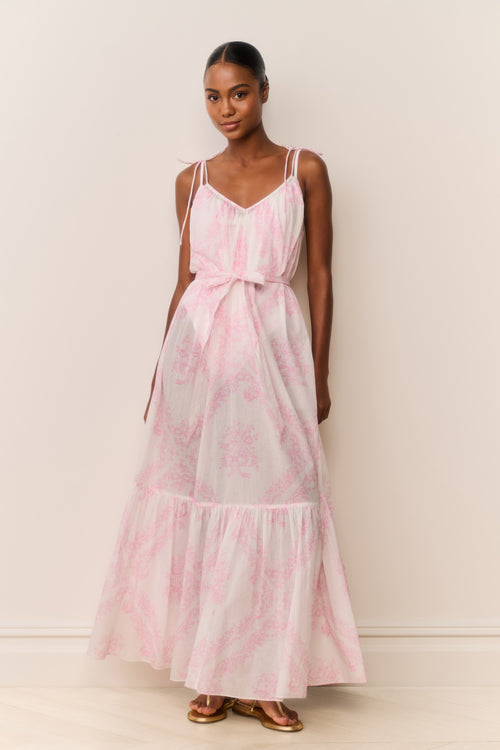 Woman wearing a pink and white patterned dress against a plain background