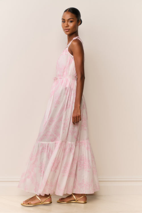 Woman wearing a pink and white patterned dress against a plain background