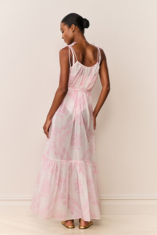 Woman wearing a pink and white patterned dress against a plain background