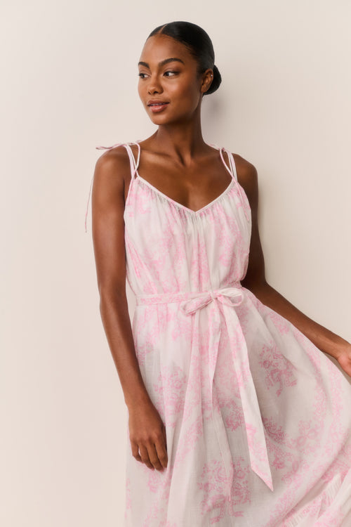 Woman wearing a pink and white patterned dress against a plain background