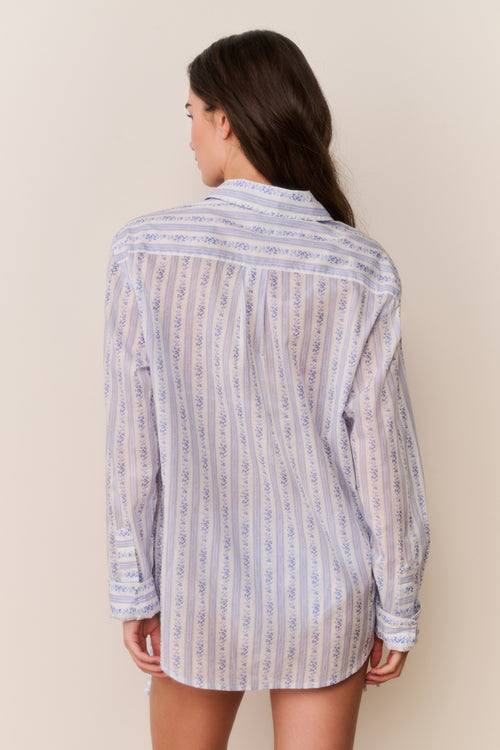 Woman wearing a floral striped shirt against a plain background