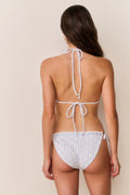Woman wearing striped floral bikini set  thin straps on a beige background