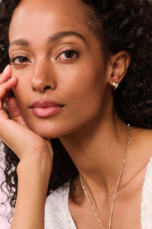 Close-up of a woman wearing a gold necklace and earring.