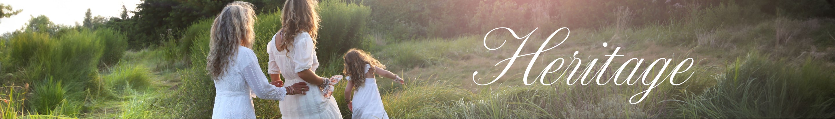 The LoveShackFancy founder walking in a field with her daughters, all wearing white dresses from the Heritage Collection