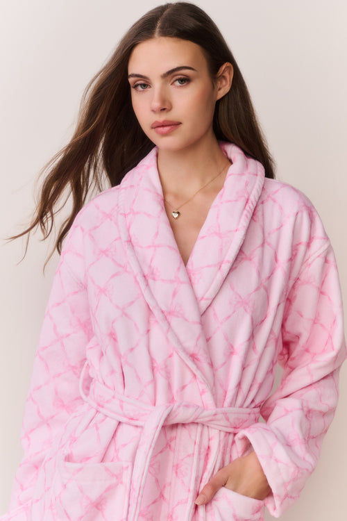 Woman wearing a pink bow print robe against a plain background