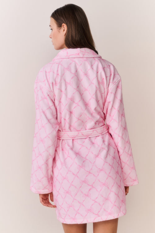 Woman wearing a pink bow print robe against a plain background