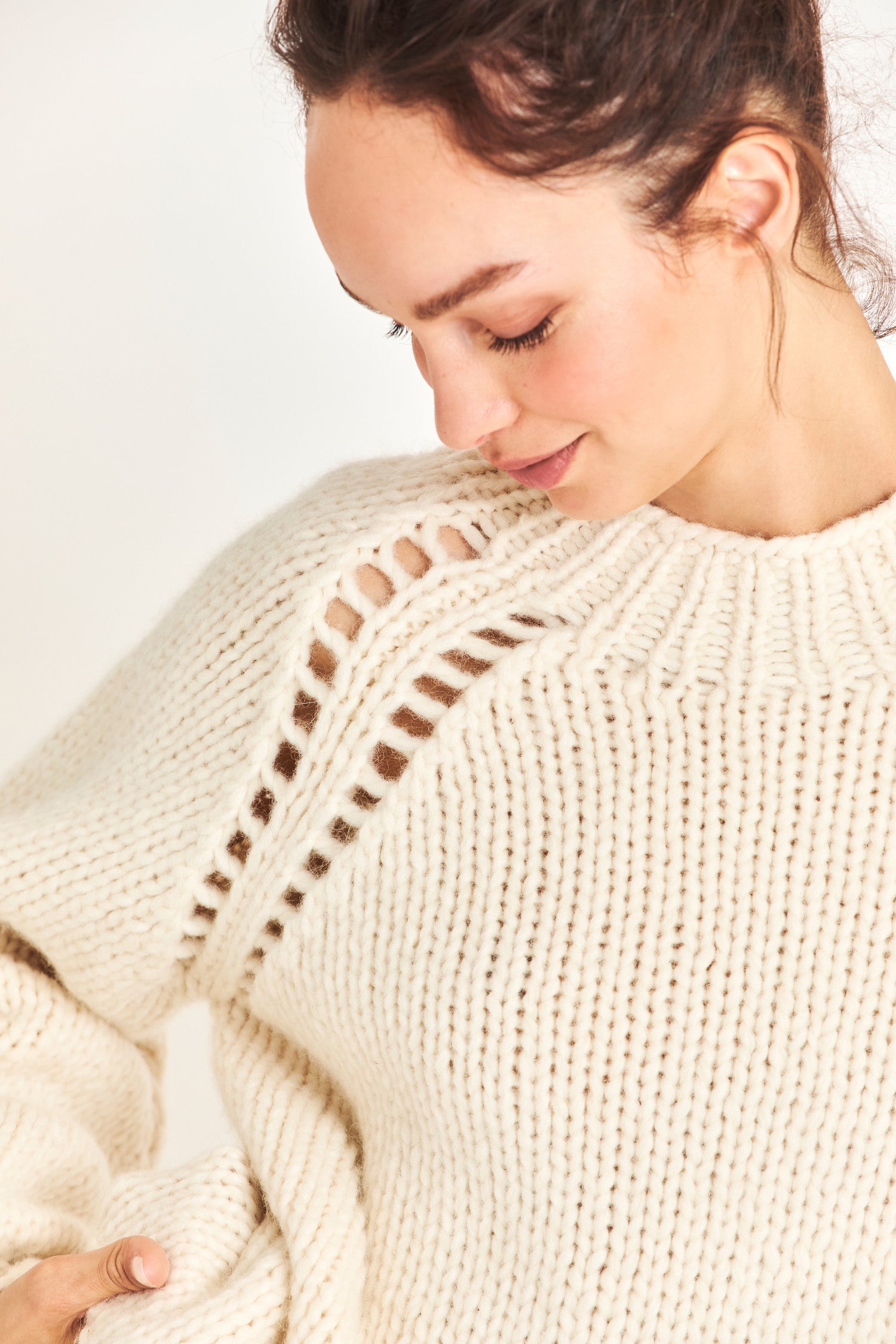 Close up image detailing knitting of white pullover sweater