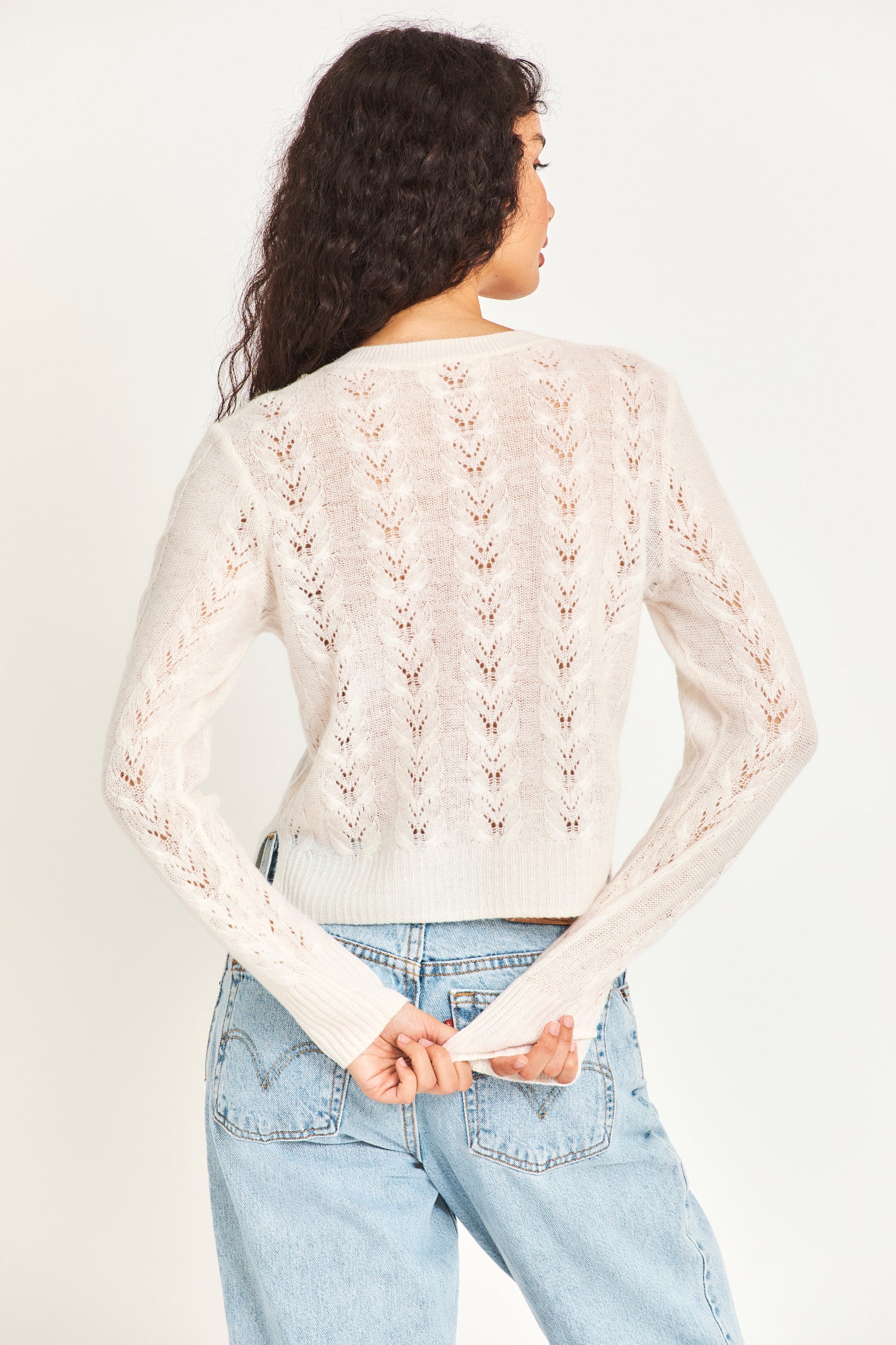  The lightweight white cable knit sweater is a cashmere wool blended sheer fabric with pointelle detailing and a hand embellished neckline with crystals and clusters of iridescent pearls. 