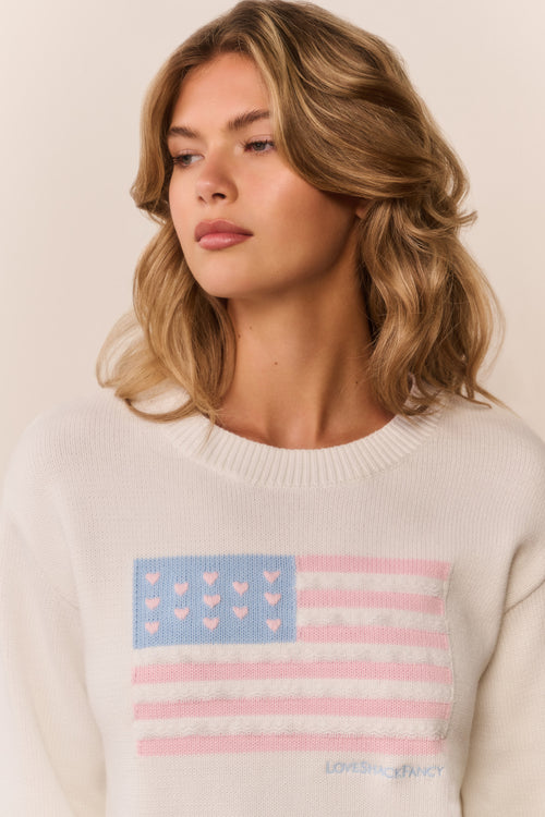 Woman wearing a sweater with an American flag design featuring hearts.