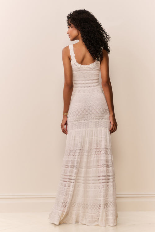 Woman wearing a white lace dress against a plain background