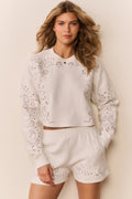 White eyelet accented pullover against a white background