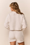 White eyelet accented pullover against a white background