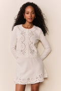 Woman wearing white eyelet trim mini skirt and matching cardigan