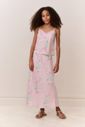 Tween wearing a pink floral skirt and top against a white background