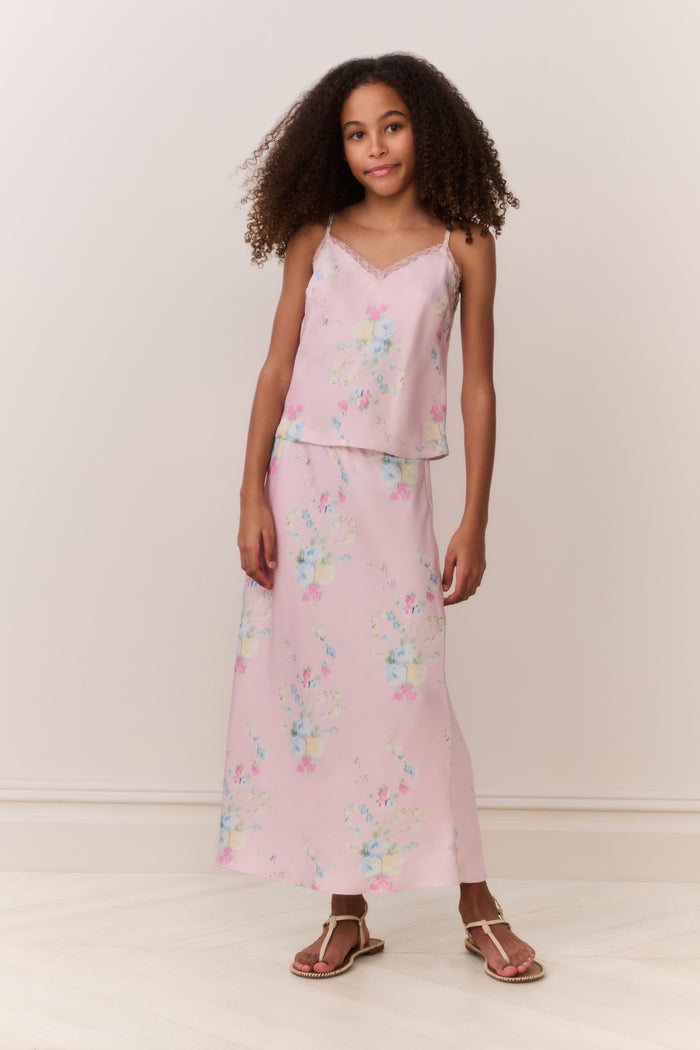 Tween wearing a pink floral skirt and top against a white background