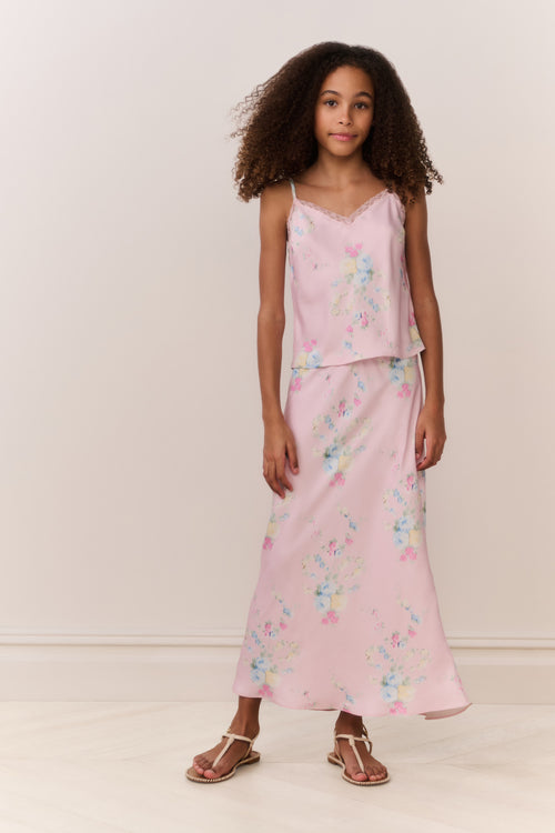 Tween wearing a pink floral skirt and top against a white background