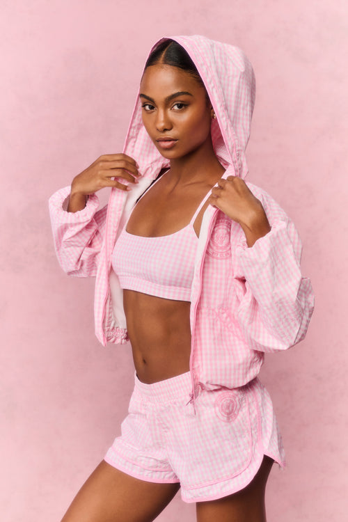 Woman wearing a pink athletic outfit with a matching jacket on a pink background
