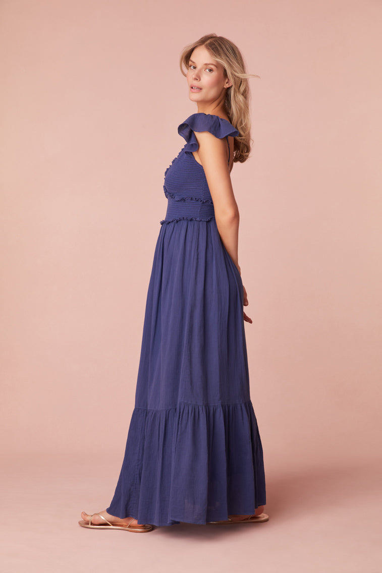 Maxi dress featuring short flutter sleeves with cascading ruffles and elastication for comfort, a v-neckline, a smocked bodice with ruffles, and a flouncy skirt.