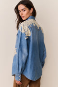 Woman wearing Blue denim shirt with floral lace embroidery on a beige background