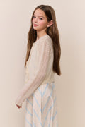 Young girl wearing a cream sweater with a beige background