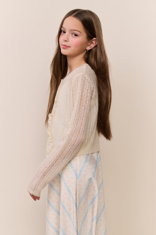 Young girl wearing a cream sweater with a beige background