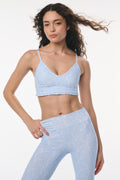 Woman wearing a light blue sports bra and leggings set on a white background