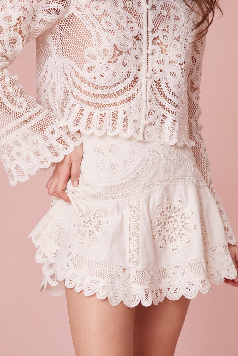 Mini skirt with intricate Battenburg lace detailing and circular rosettes along the skirt panels.