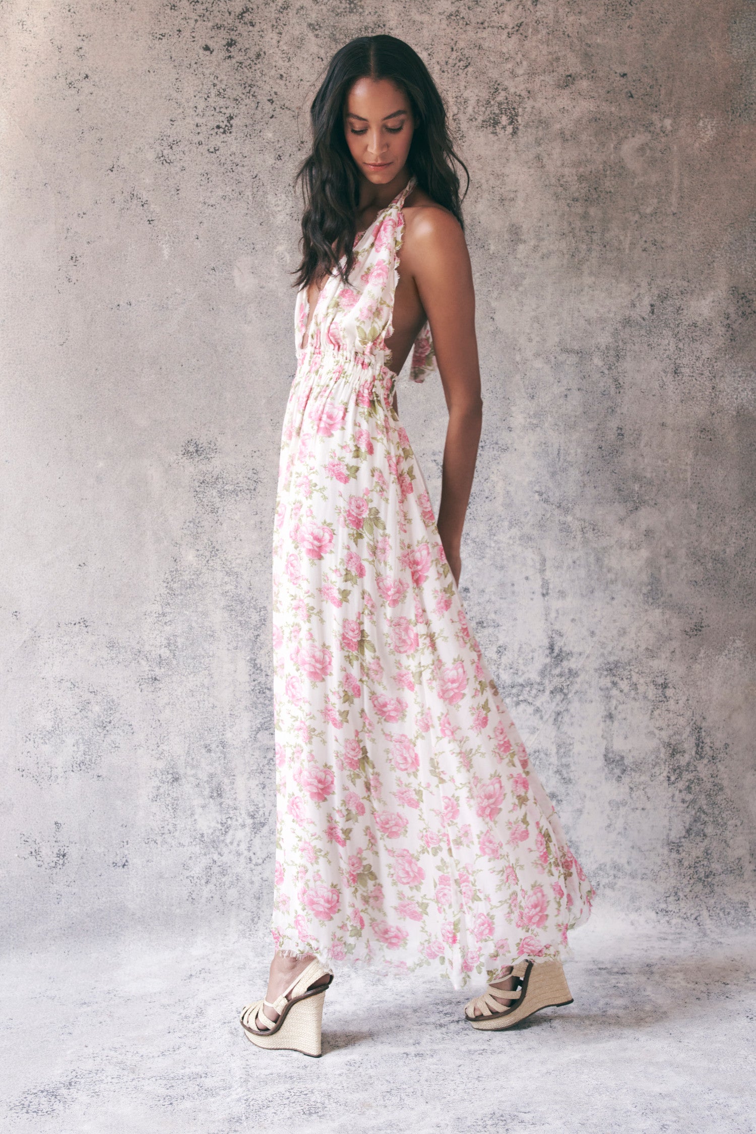 Side image of model wearing pink floral halter maxi dress