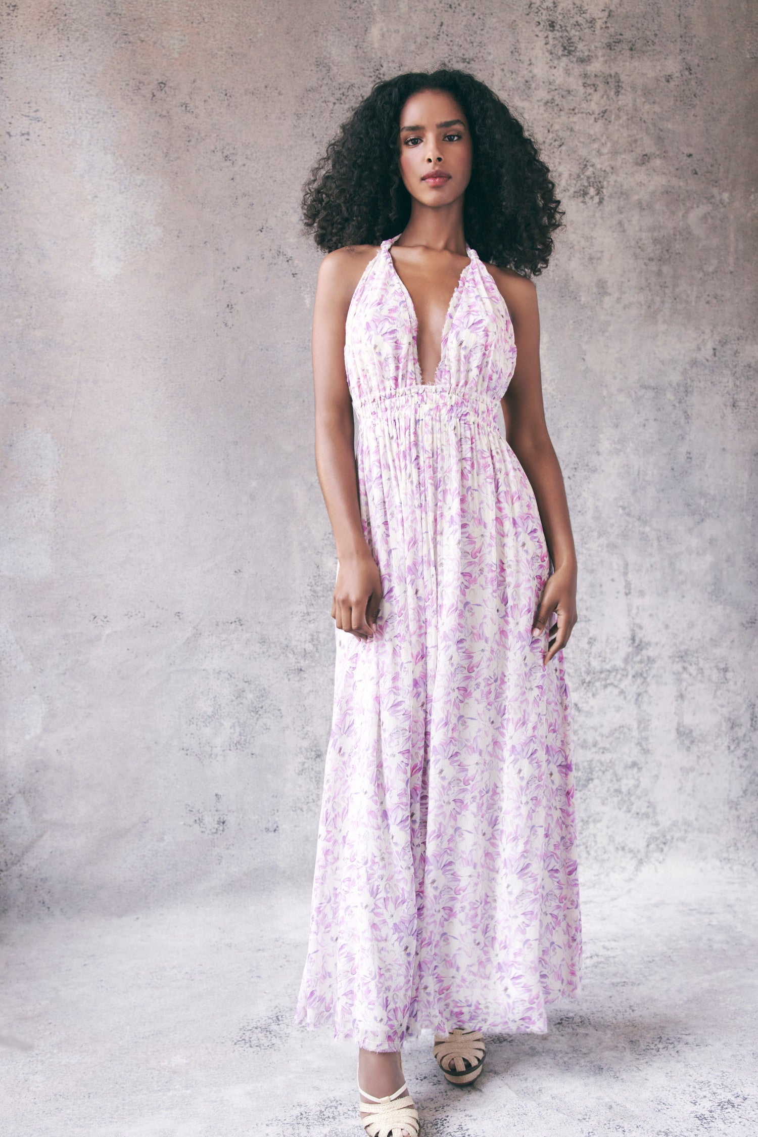 Model wearing white and purple floral halter maxi dress