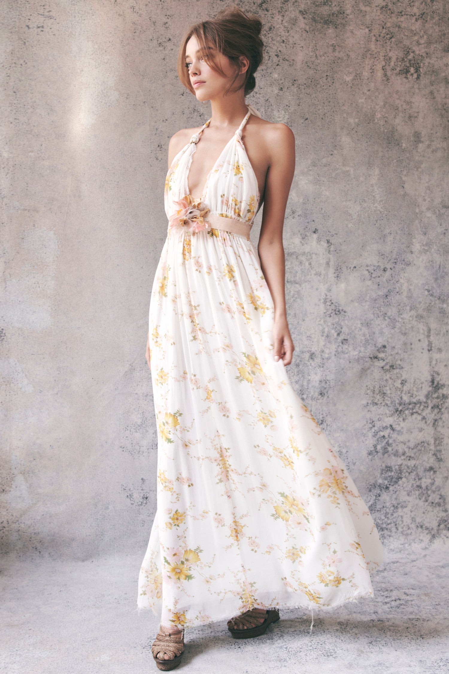Model wearing white and yellow floral halter maxi dress