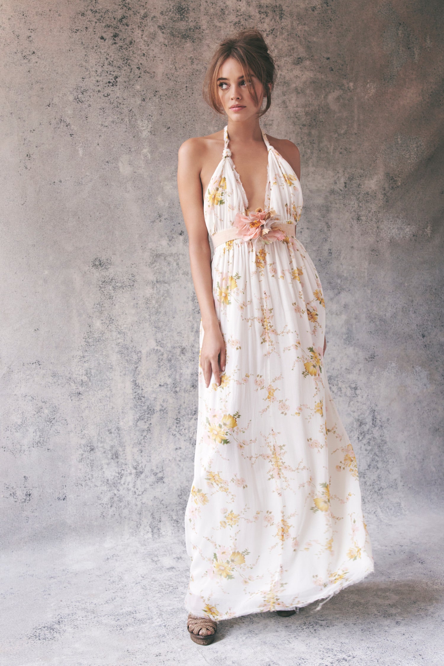 Model wearing white and yellow floral halter maxi dress