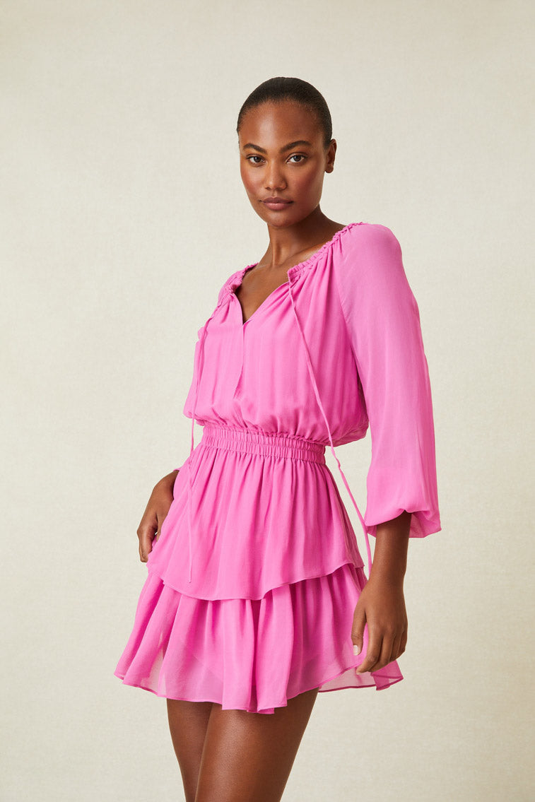 Model wearing pink long sleeve mini dress with blousy top and tiered ruffle skirt.
