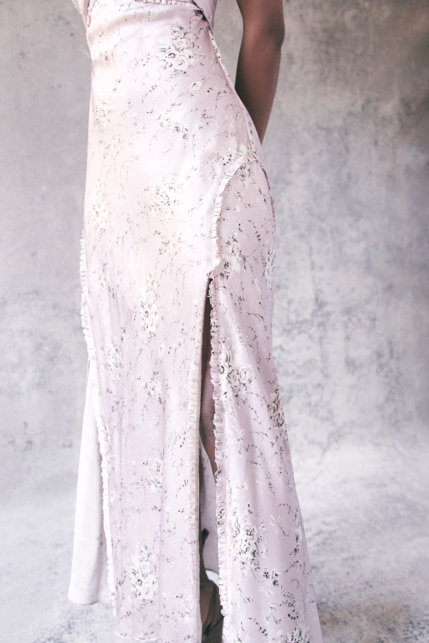 Close up image detailing ruffle trim and pattern on light pink floral maxi dress