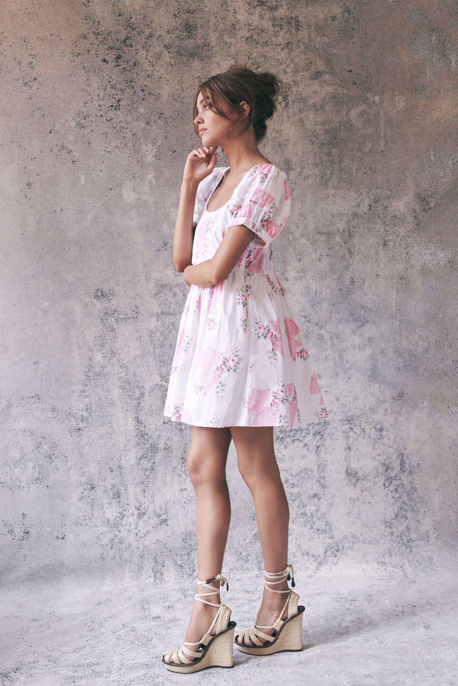 Side image of model wearing pink and white floral babydoll mini dress with puff sleeves