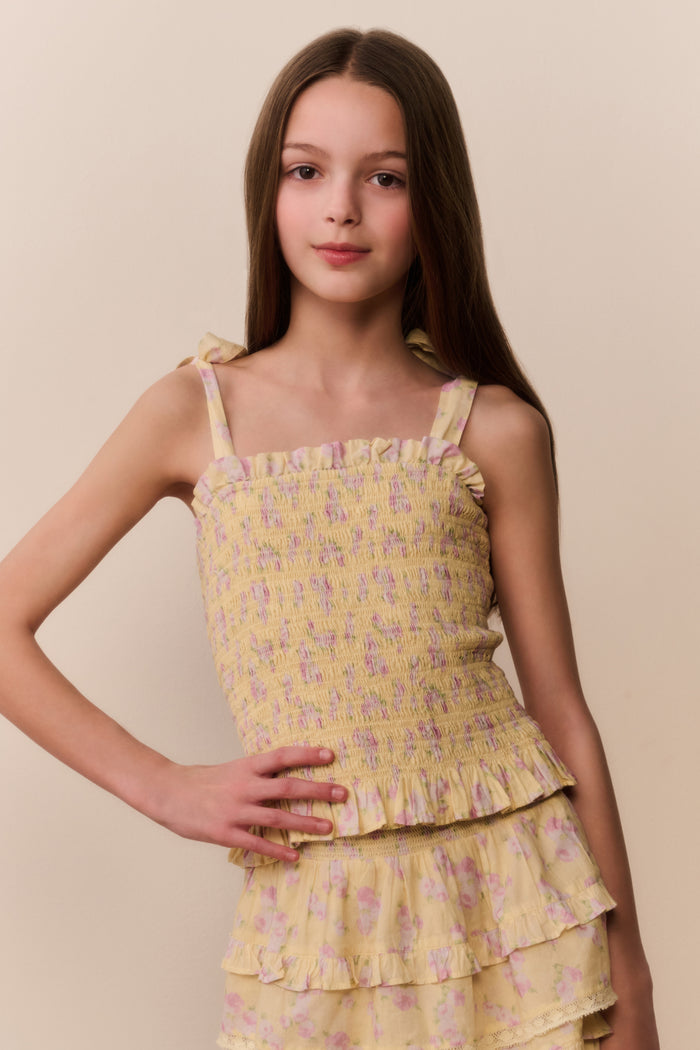 Young girl wearing a yellow floral set against a beige background