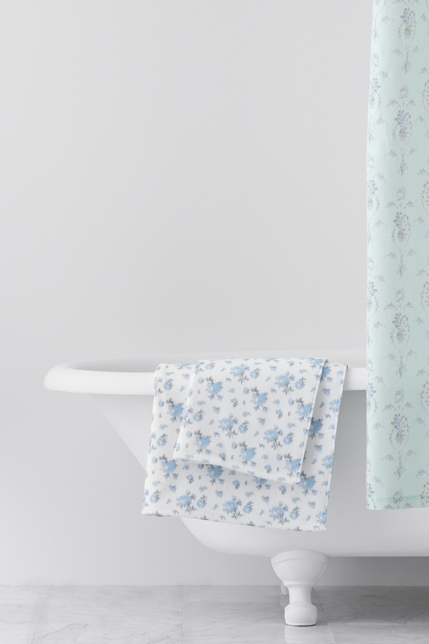 vintage-inspired delicate repeating mini floral print bath towel in a soft blue against a white back